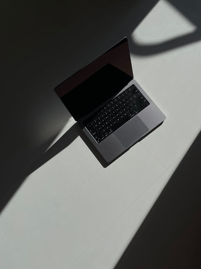 home-bg-img Artistic overhead view of an open laptop casting shadows on a flat surface.